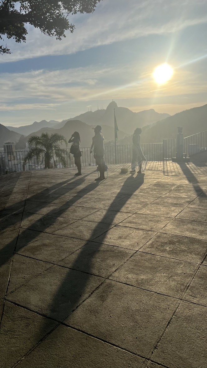 Travelers silhouetted at sunset on the terrace with Christ the Redeemer beyond
