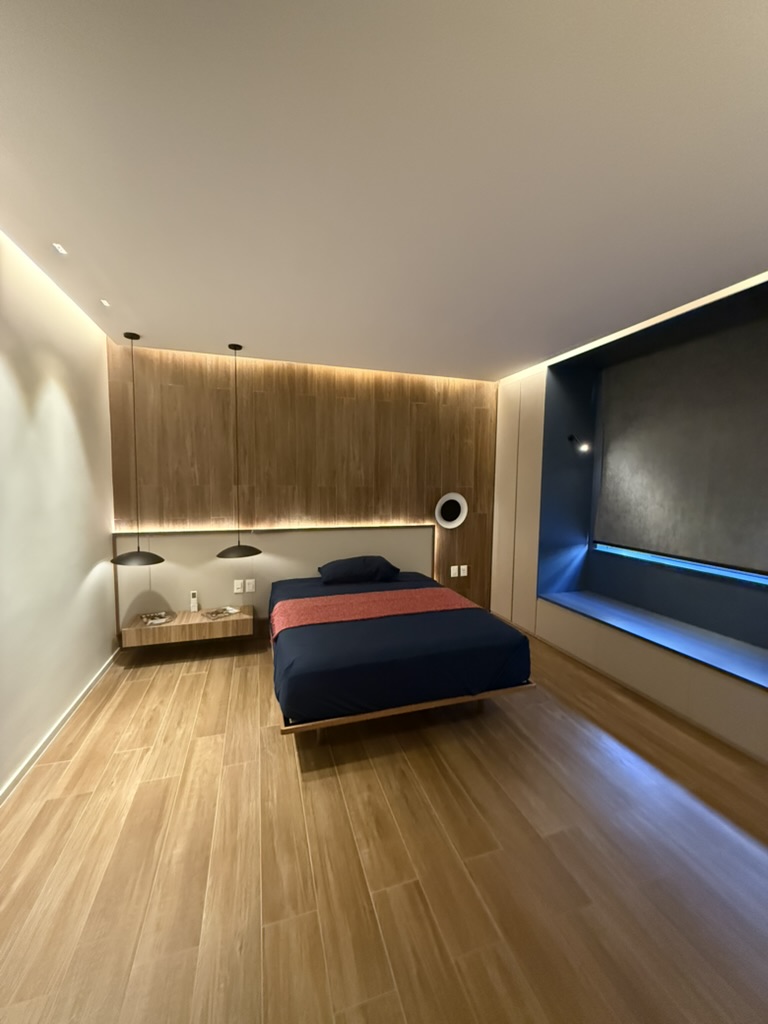 The suite at night, warm wood headboard beside the lit blue niche.