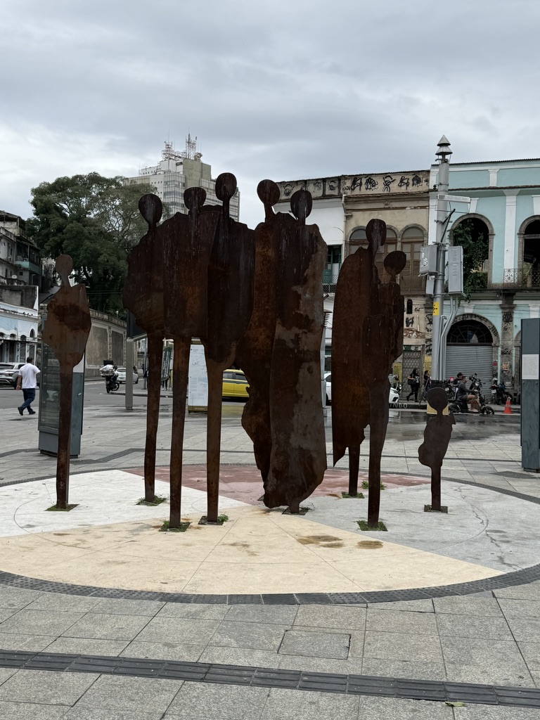 Silhouetted figures of a public memorial standing in the contemporary city