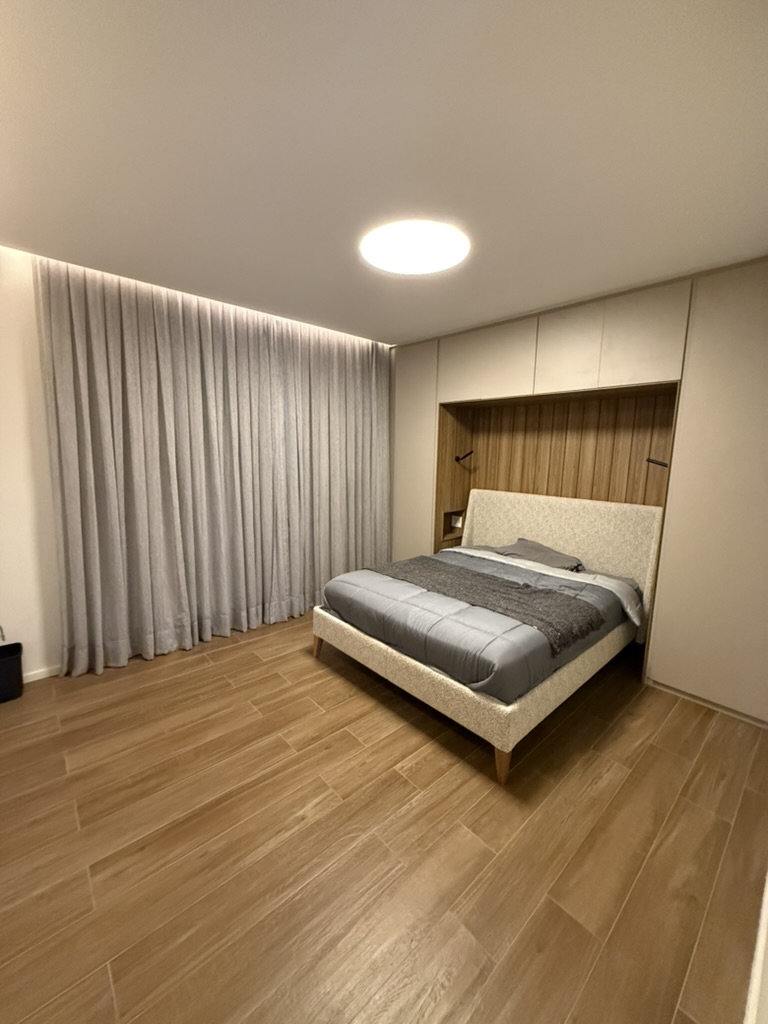 The suite by evening, linen curtains drawn the length of the wall.