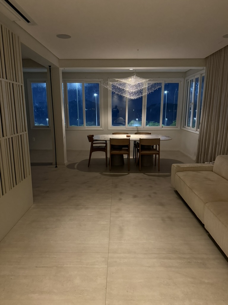 The dining table at night, the chandelier lit above the marble.